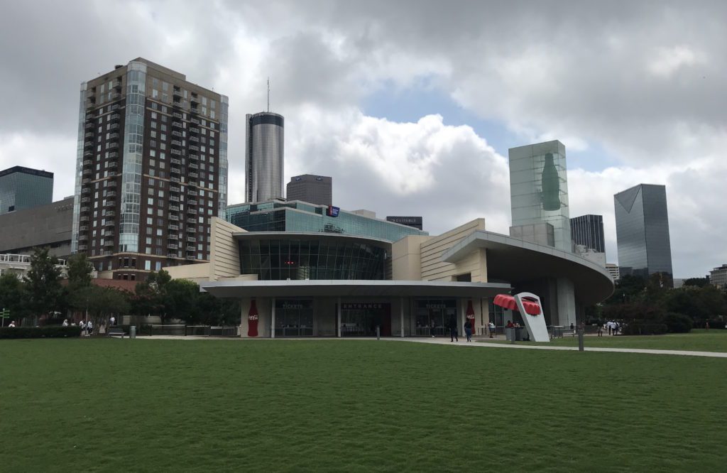 World of Coca-Cola with a lawn and a large building with tall buildings in the background
