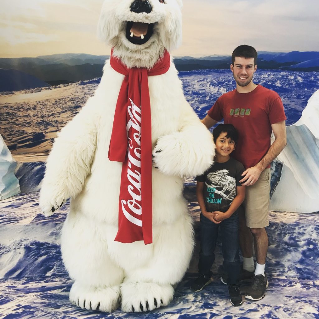 a man and child posing with a polar bear mascot