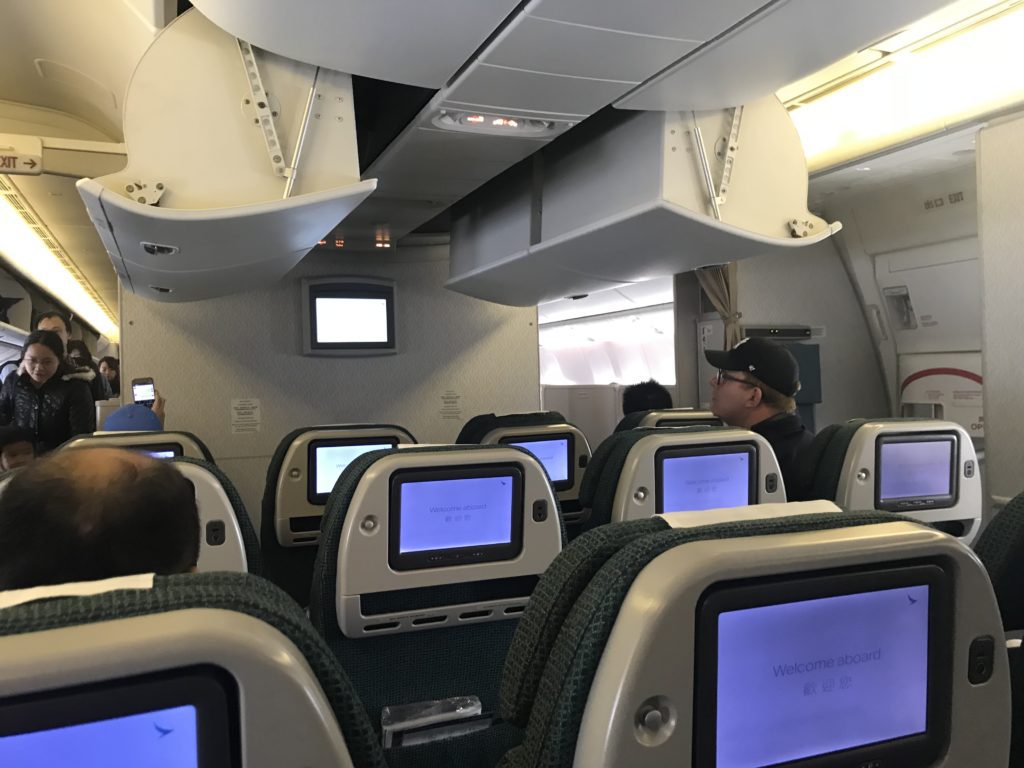 a group of people sitting in an airplane with monitors