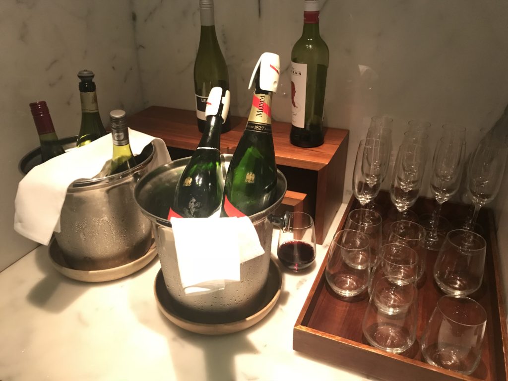 a group of wine bottles in a bucket and a tray of wine glasses