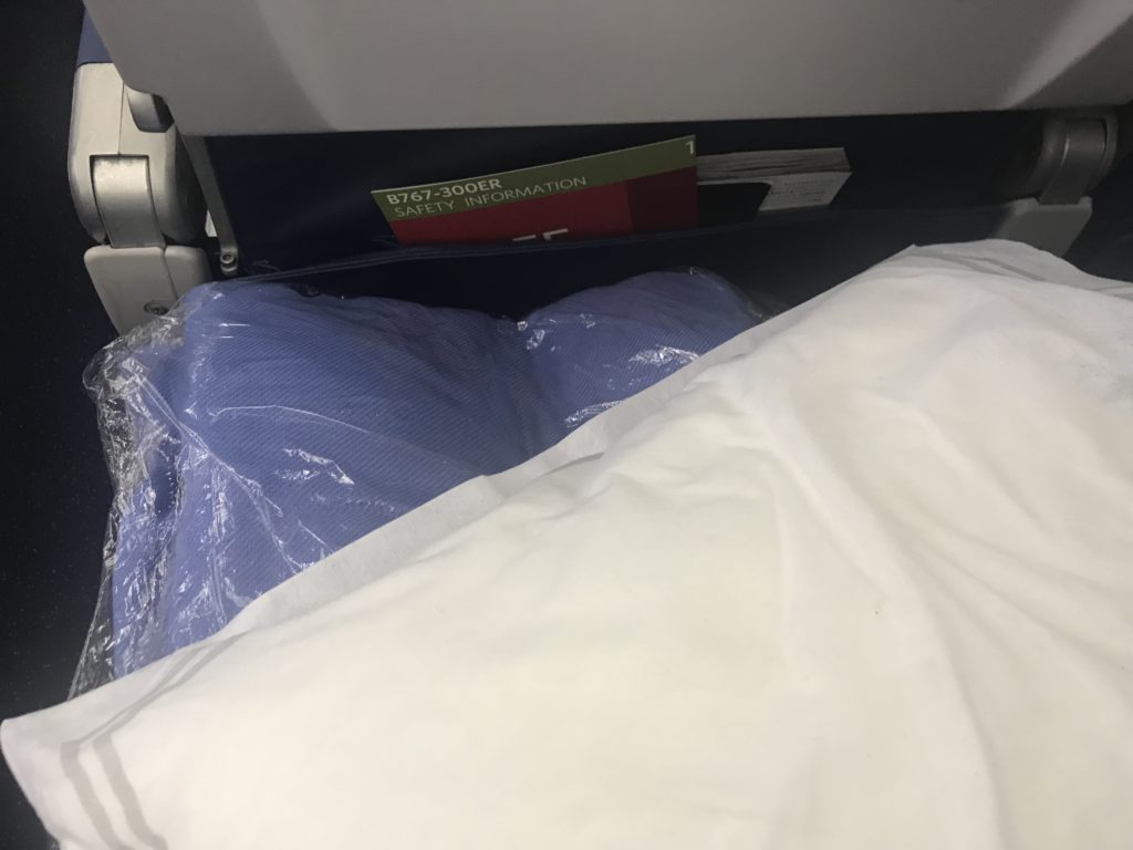 a bed with a blue blanket and a white pillow