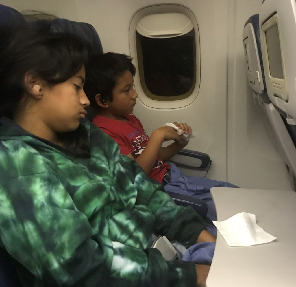 a boy and girl sitting on an airplane