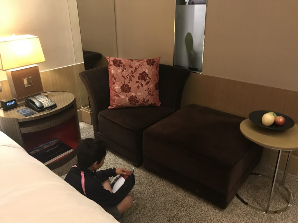 a child sitting on the floor in a room with a couch and a lamp