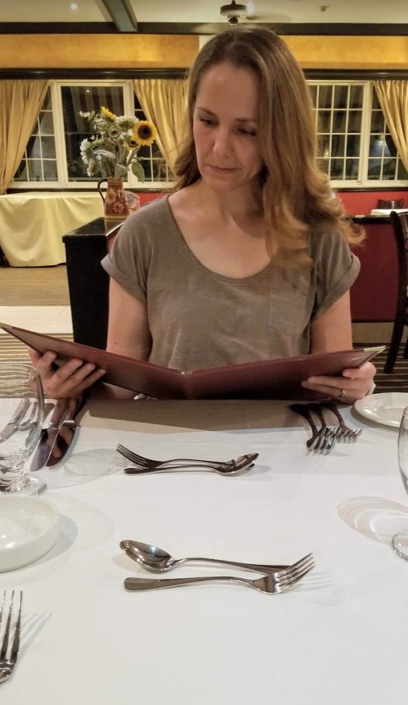 a woman sitting at a table with a menu