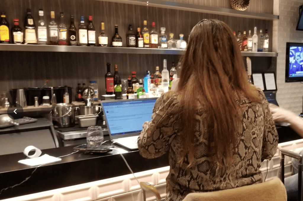 a woman sitting at a bar with a laptop
