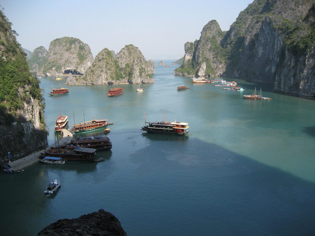 boats in a body of water with mountains in the background with Ha Long Bay in the background