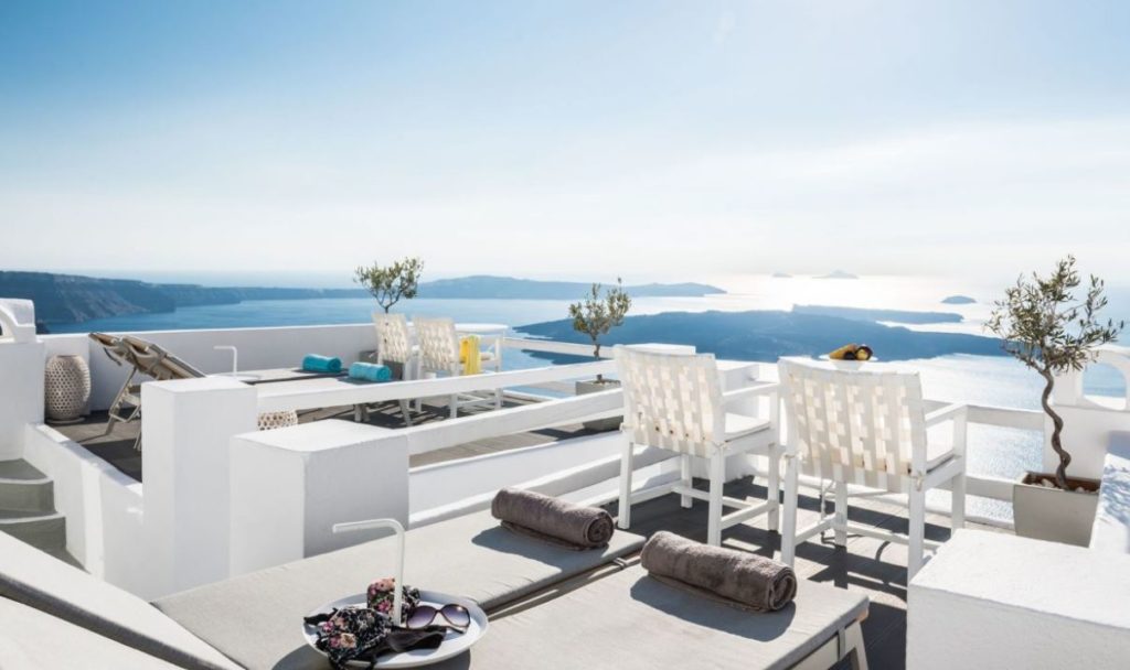 a white chairs and a table on a rooftop overlooking water