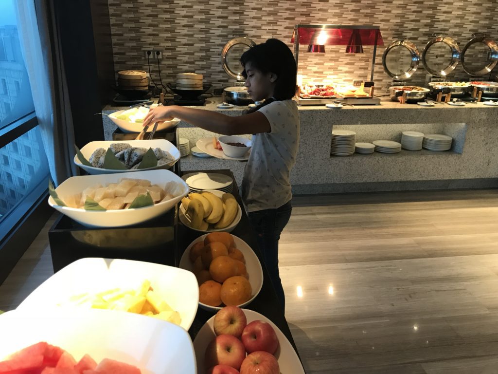 a woman standing in front of a buffet table full of fruit