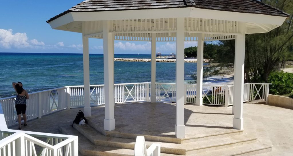 a white gazebo with a white railing overlooking the ocean