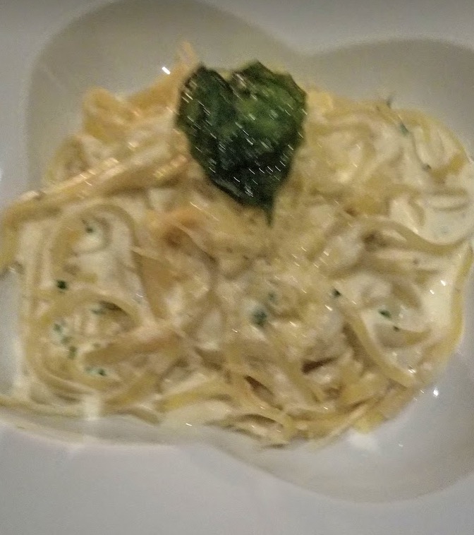 a plate of pasta with a green leaf