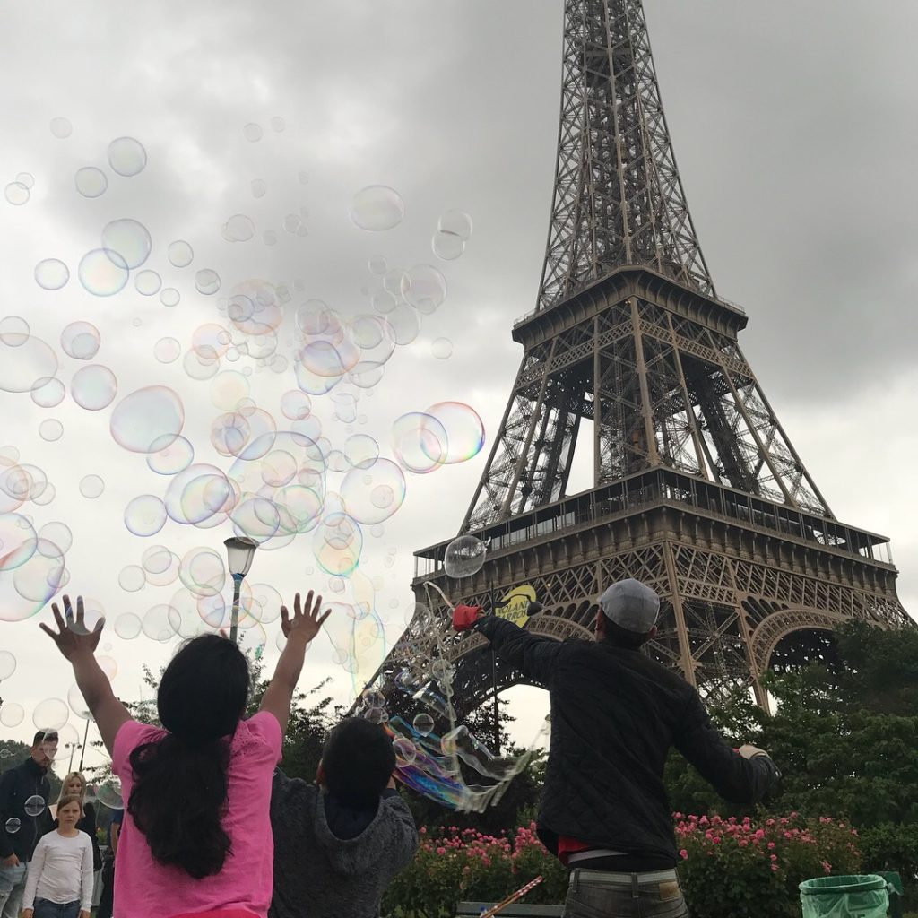 a group of people outside with bubbles in front of the eiffel tower