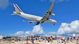 a large airplane flying over a beach