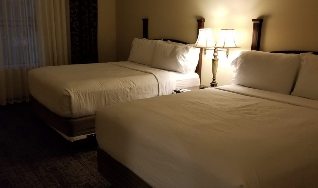 two beds with white sheets and lamps
