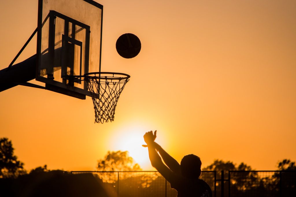 a person playing basketball at sunset