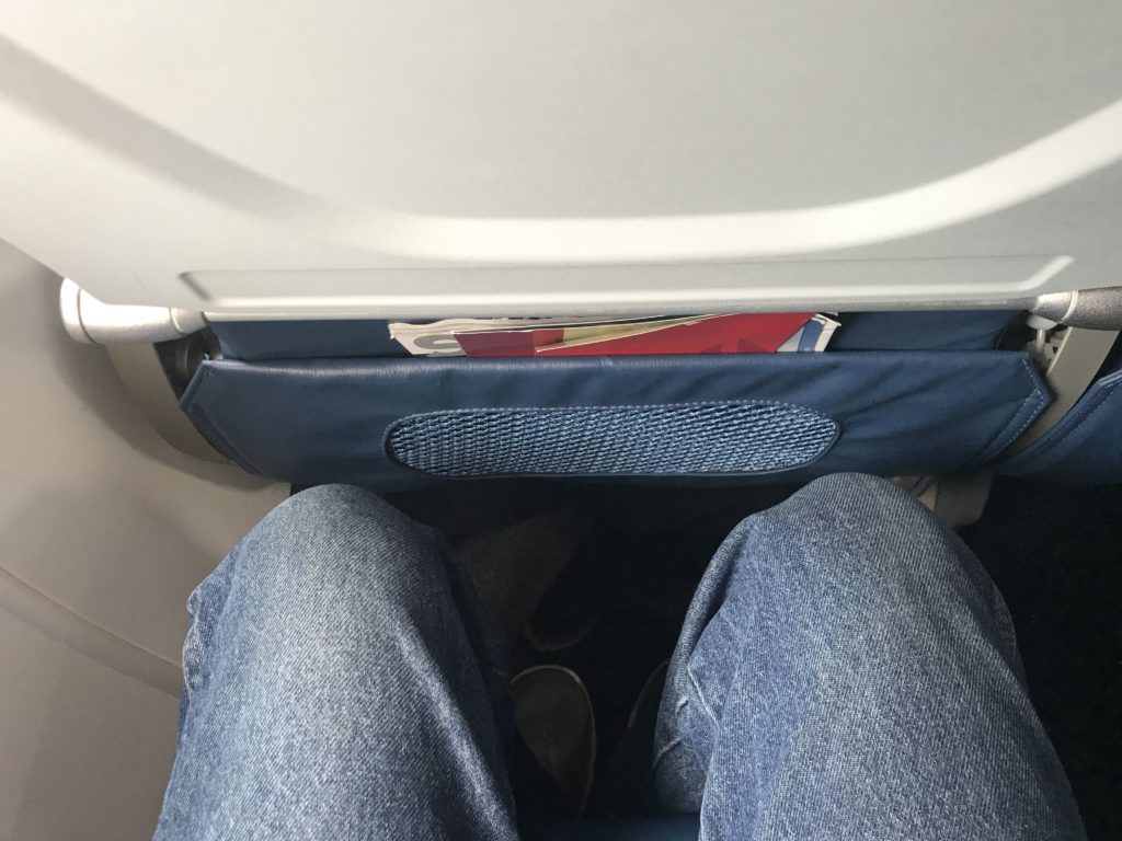 a person's legs and a seat in an airplane