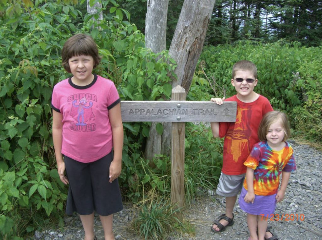 a group of kids standing next to a sign