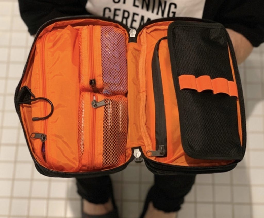 a person holding an orange and black bag