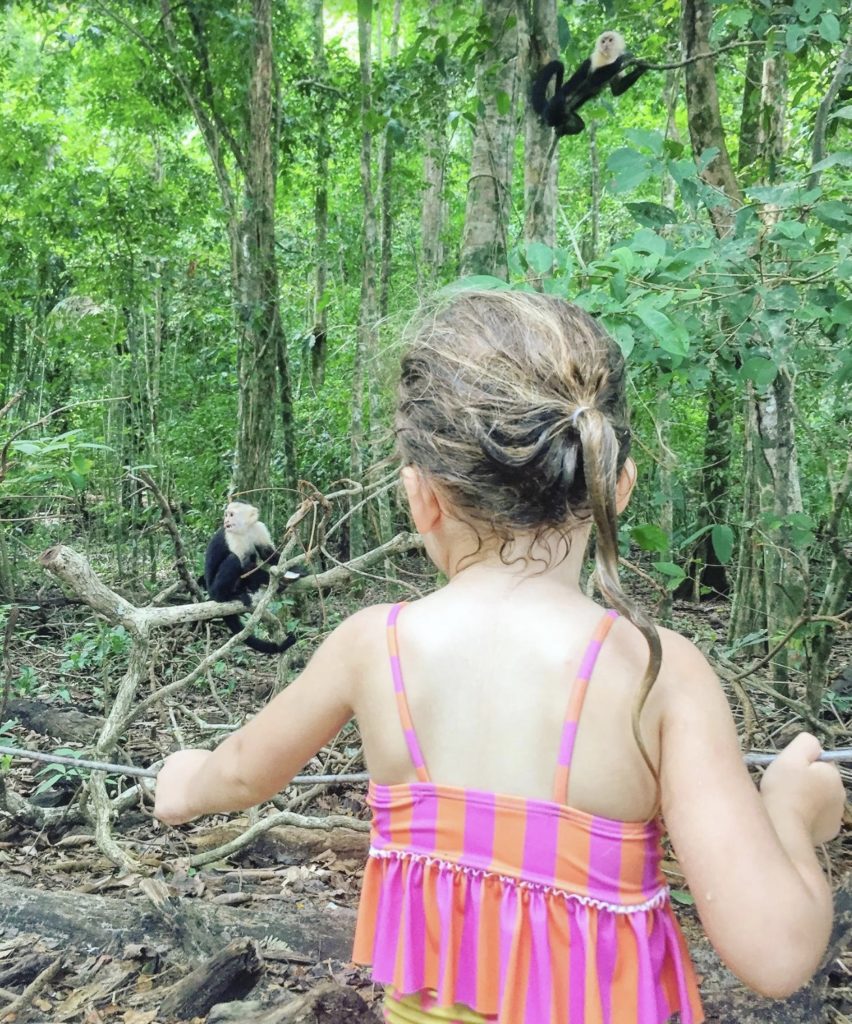 a girl looking at a monkey in the woods
