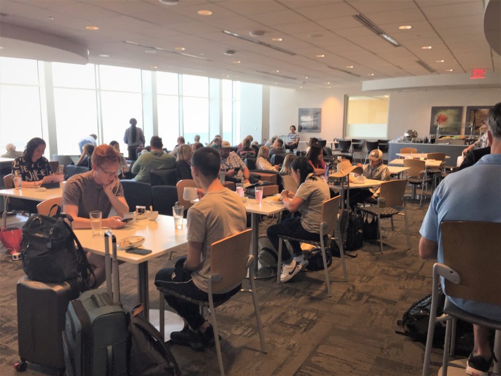 a group of people sitting at tables in a room with windows