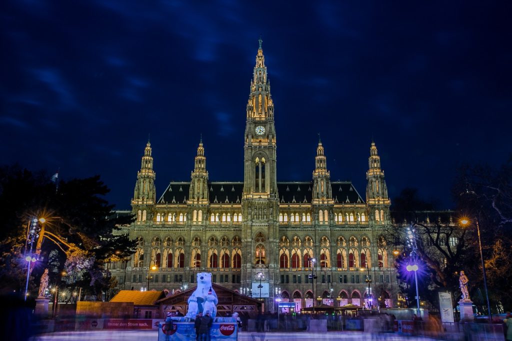 a large building with a clock tower with Rathaus, Vienna in the background