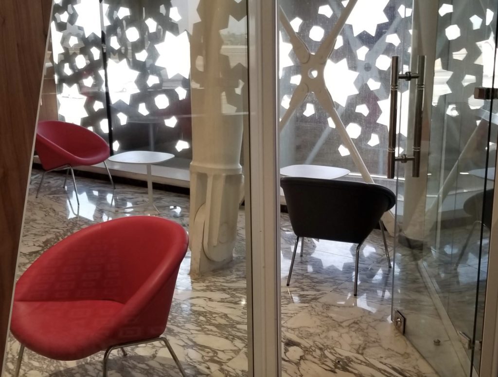 a glass door with a red chair and a black table