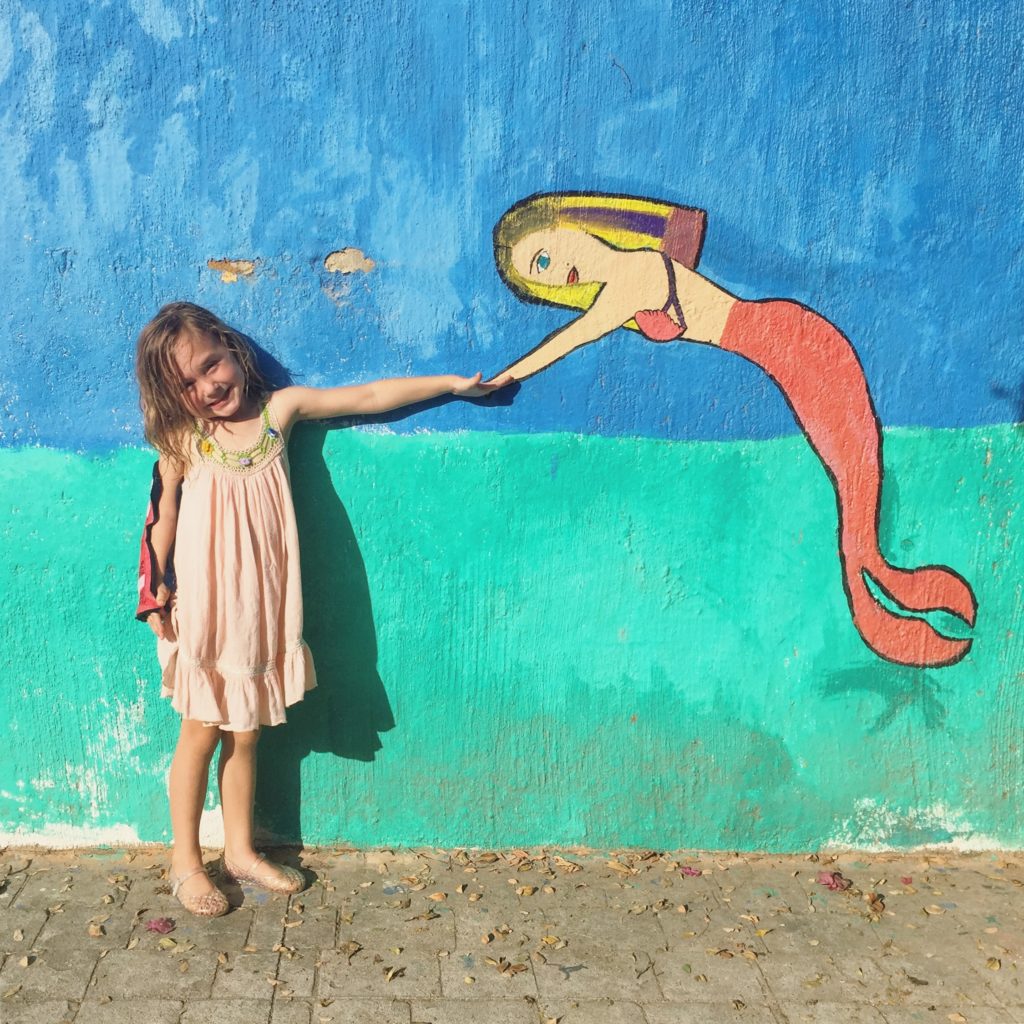 a girl touching a mermaid's hand