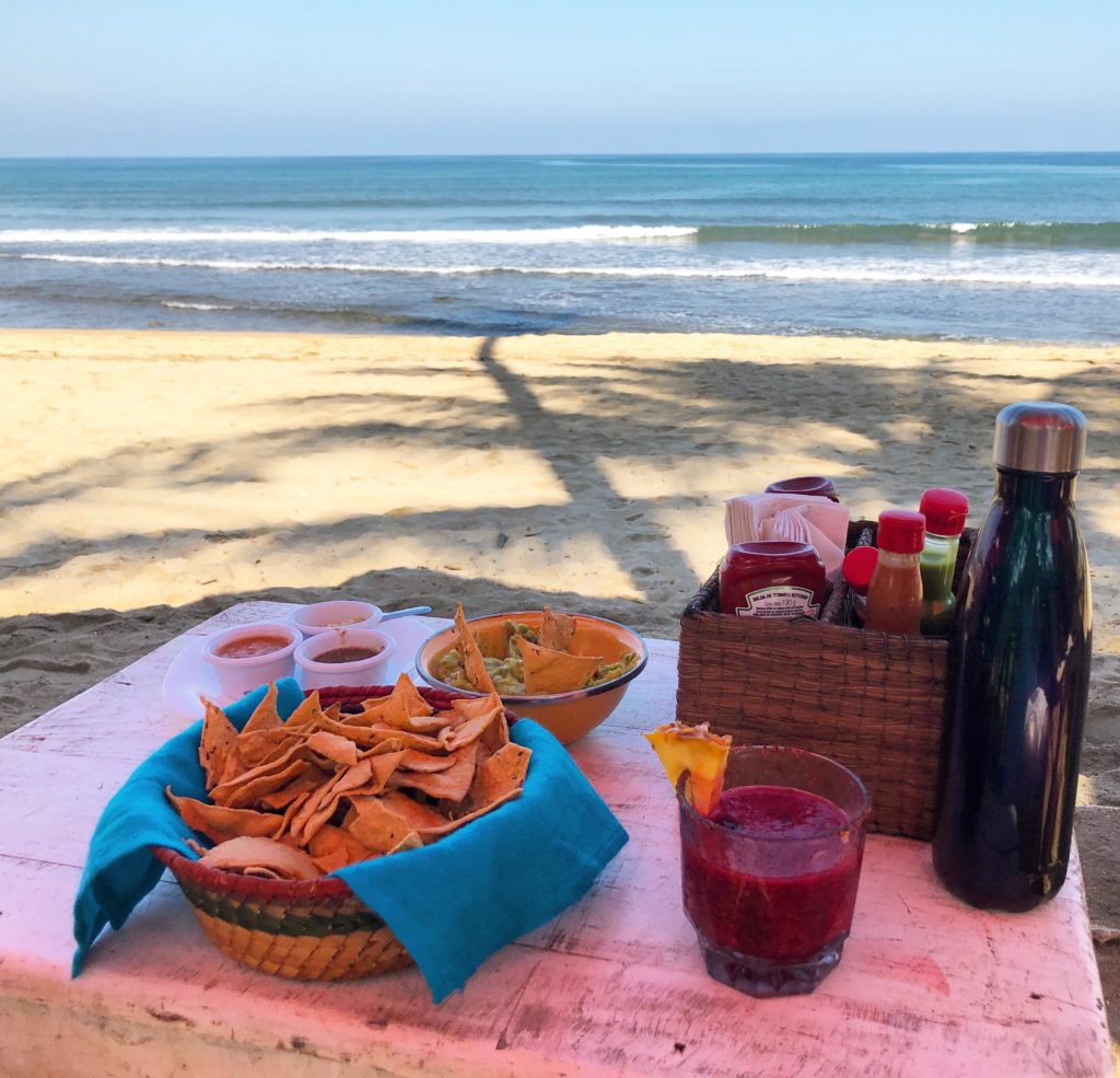 a table with food and drinks on the beach