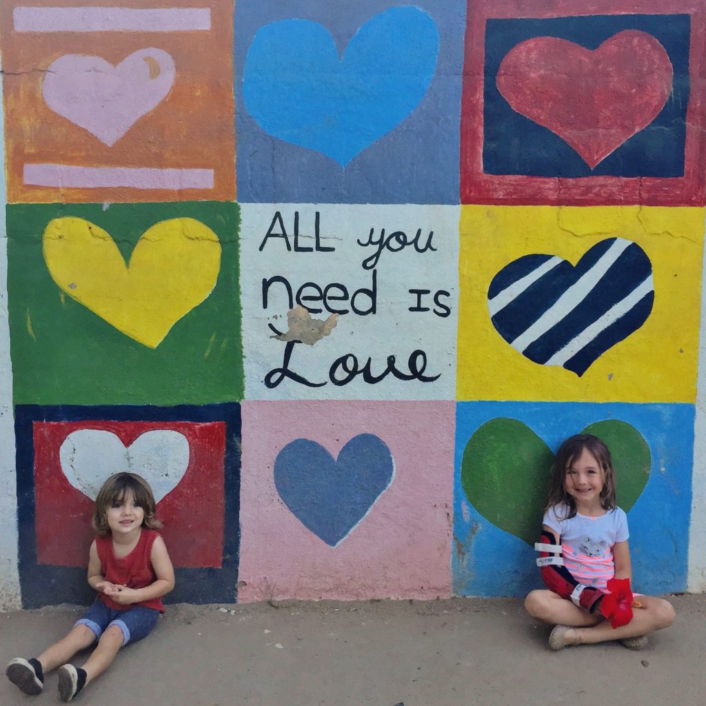 two children sitting in front of a wall with hearts