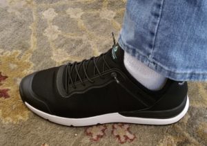 a person's foot wearing black and white sneakers