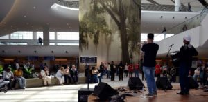 a man playing a flute in a large room with people sitting on a bench