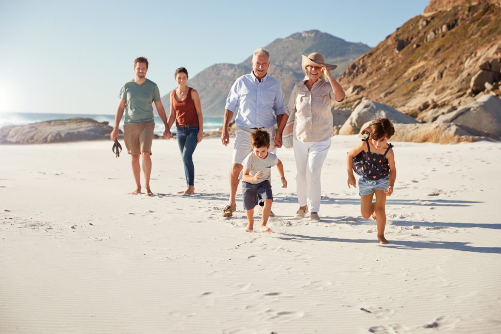 Multiple generations of a family walk on a beach.