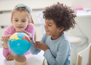 Two kids look at a globe