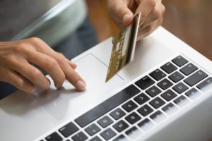 A person uses a credit card at a computer.