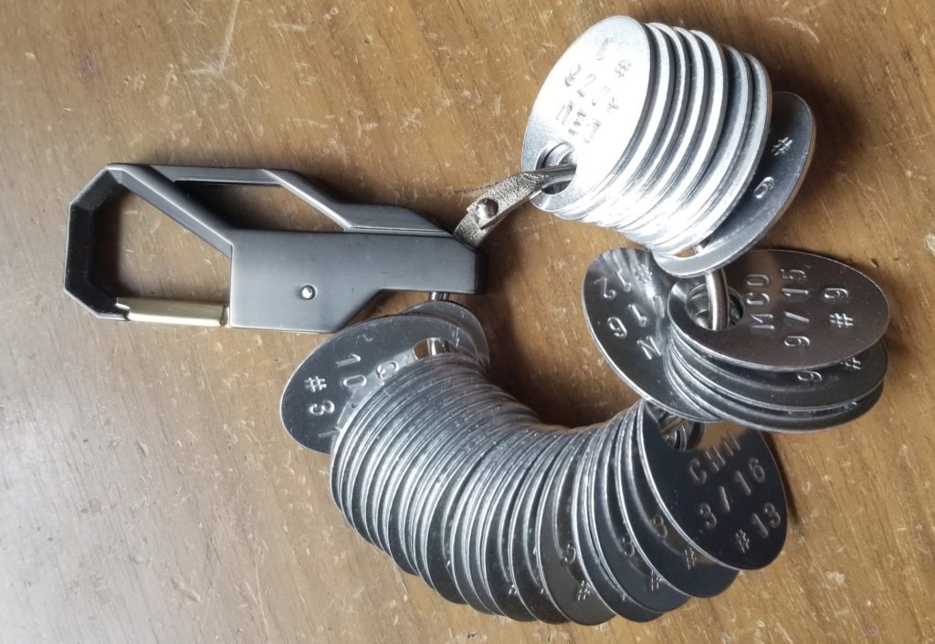 a group of metal keychains on a wood surface
