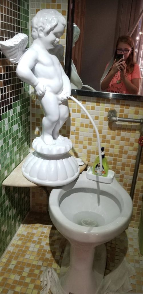 a white statue next to a toilet