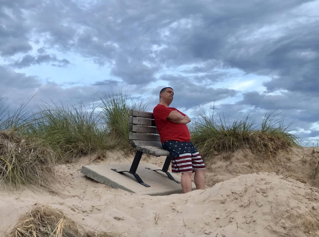 a man sitting on a bench in the sand