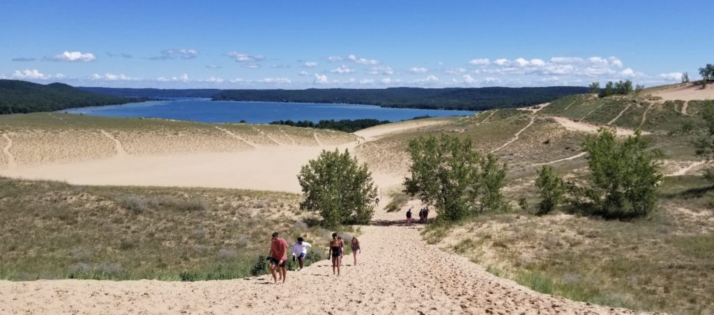 a group of people walking up a sand hill