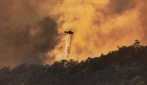A helicopter dumps water on a wildfire.