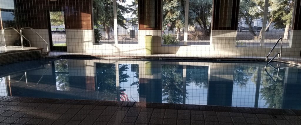 a pool with a reflection of trees and a building