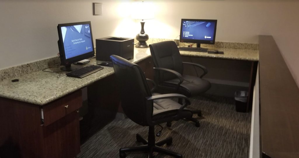 a desk with two computers and a lamp