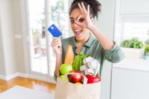 a woman holding a bag of groceries and a credit card