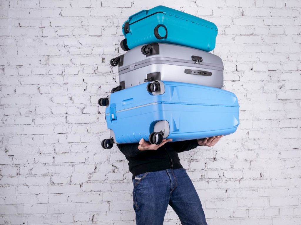 a person holding a stack of luggage