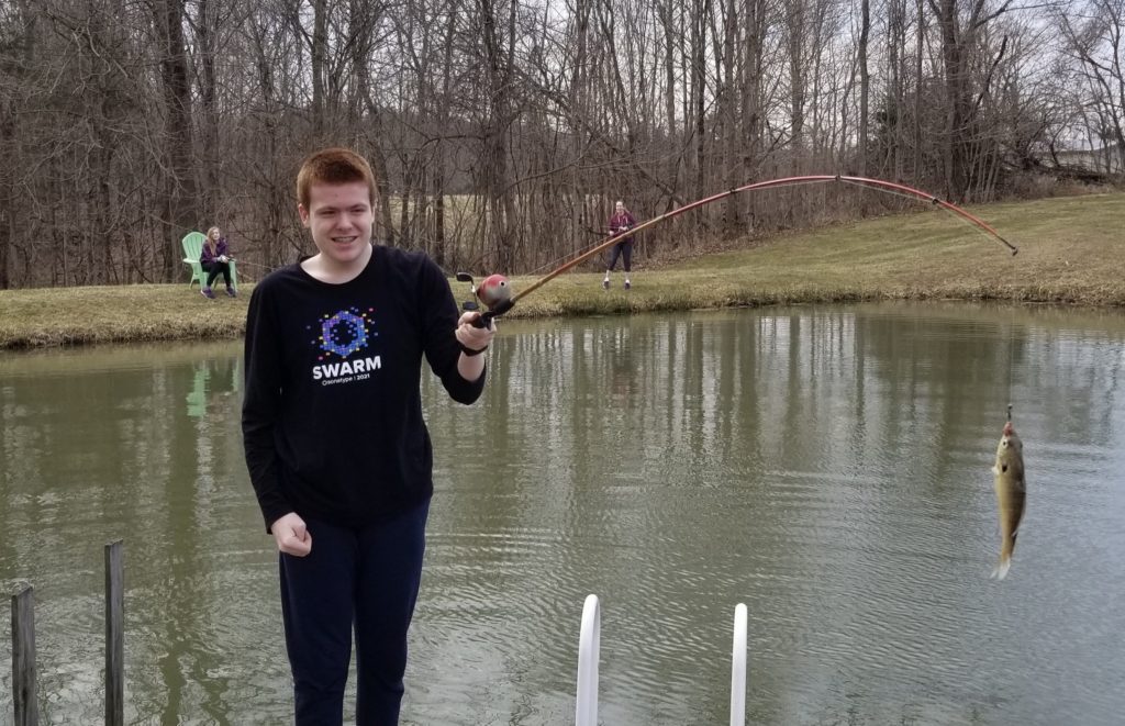 a boy holding a fishing pole in a pond