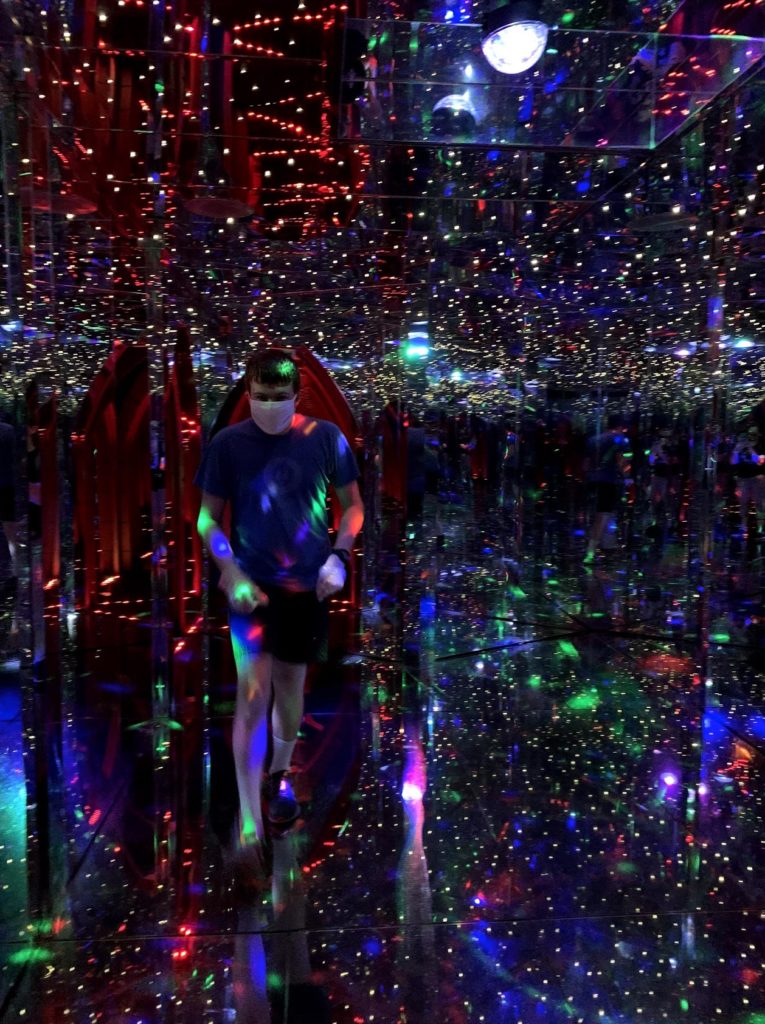 a man in a mask in a mirror room with lights