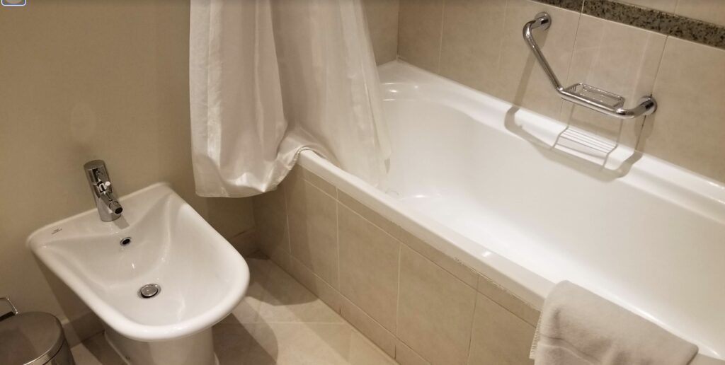 a white shower curtain next to a bathtub