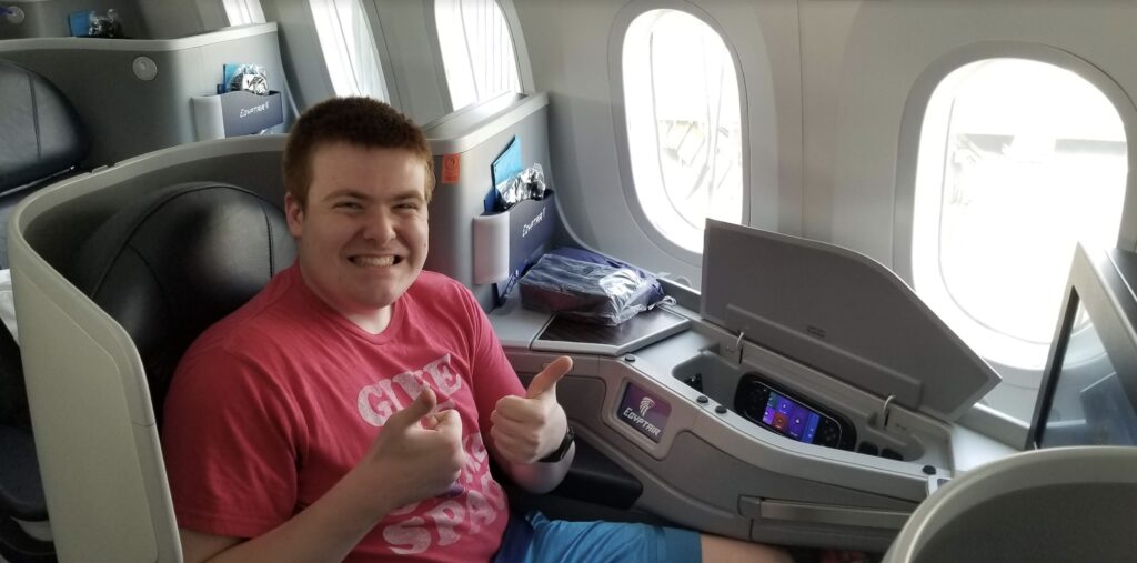 a man sitting in an airplane with two thumbs up