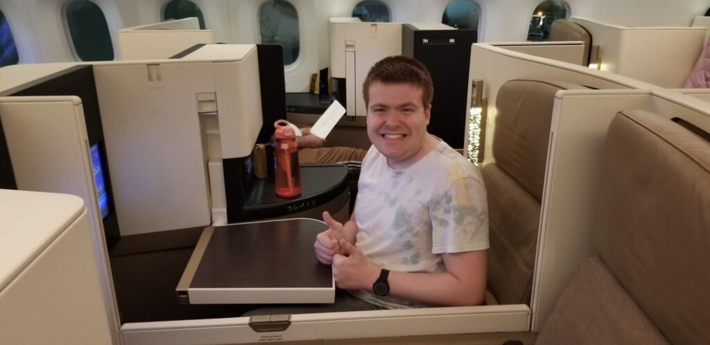 a man sitting in an airplane seat giving a thumbs up