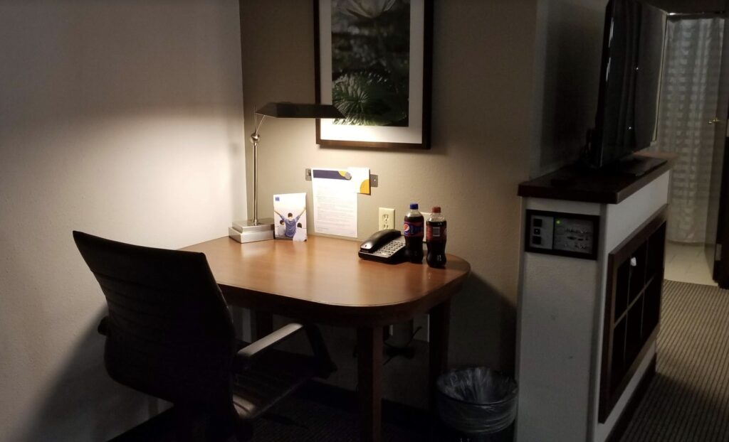 a desk with a lamp and two soda bottles on it