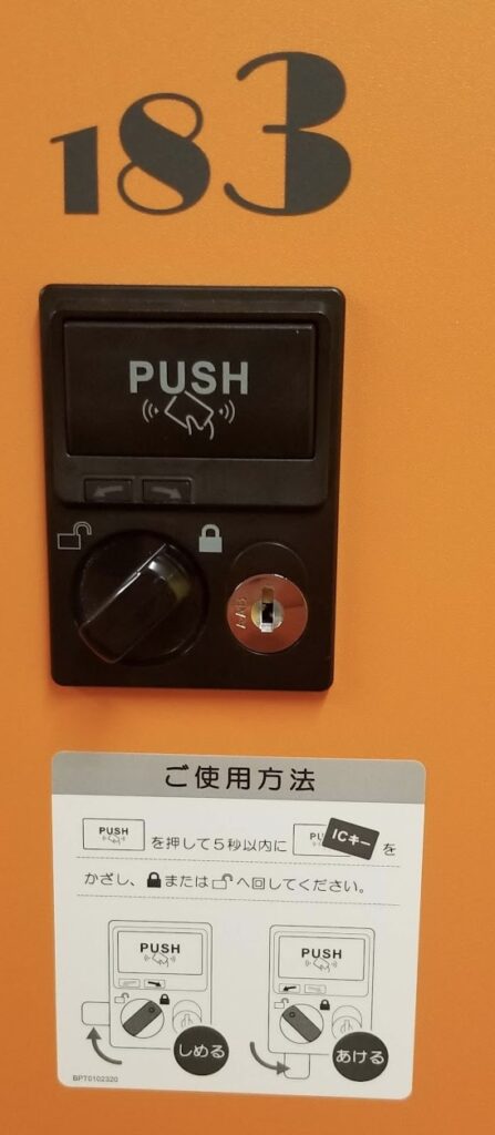 a black box with a keyhole and a button on an orange wall