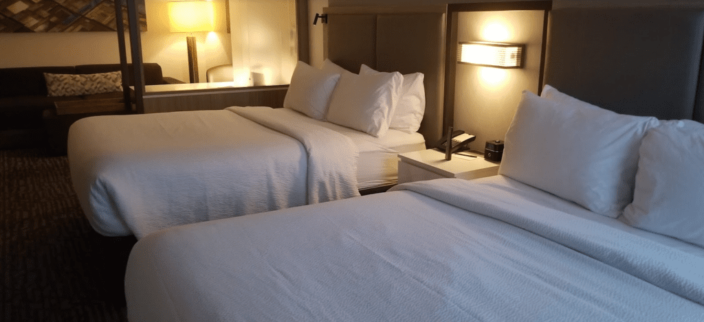 two beds with white sheets and a lamp